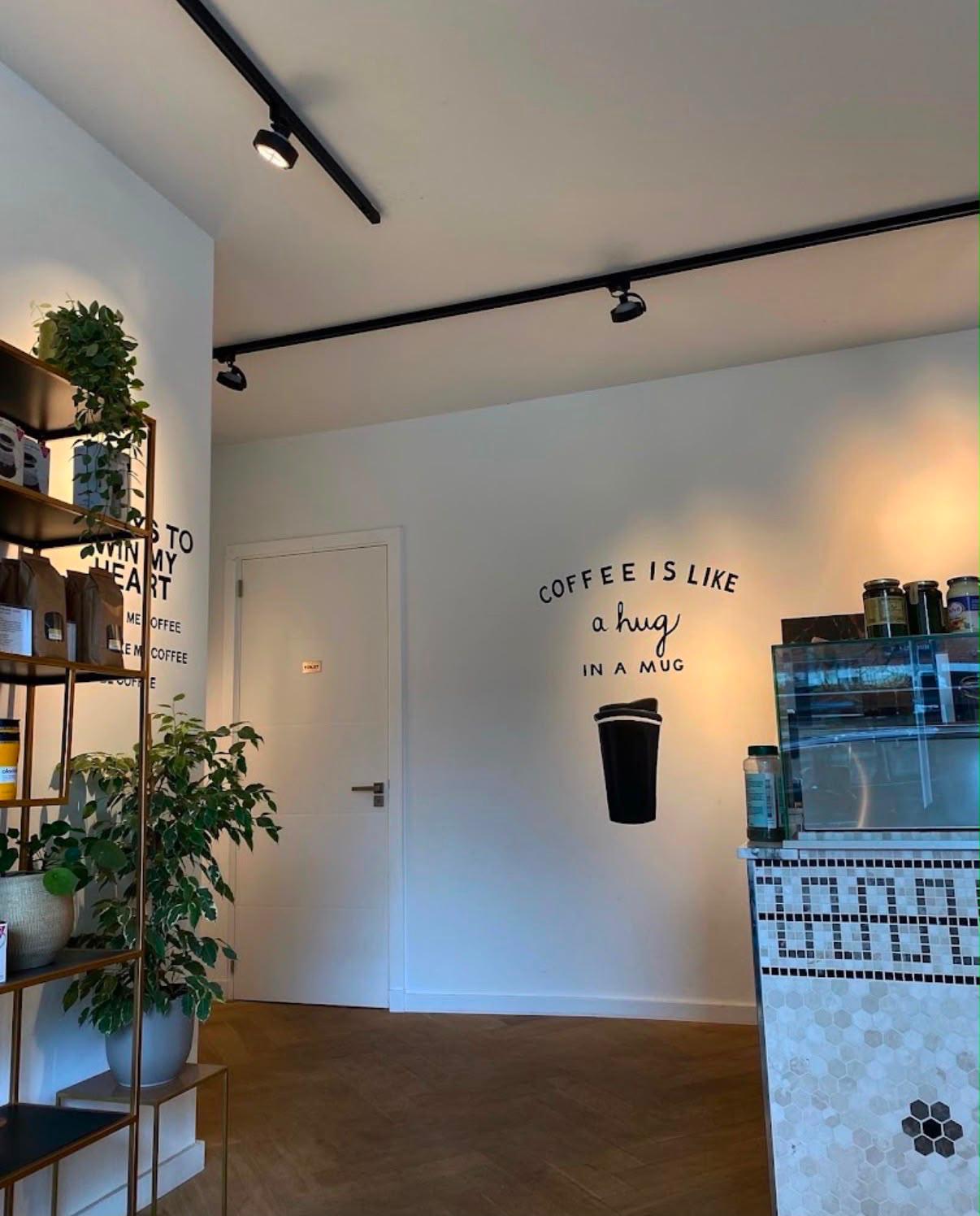 Muurtekst: coffee is like a hug in a mug naast de toonbank